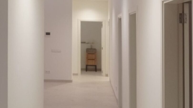 Heller, moderner Flur der Neubau-Finca in Manacor mit weißen Wänden, Einbaustrahlern und hochwertigen Türen.