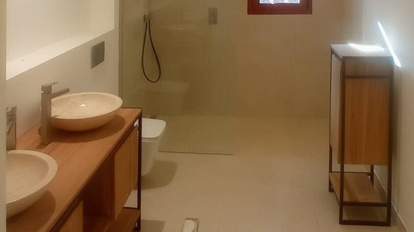 Modernes Badezimmer der Finca Manacor mit Doppelwaschbecken, bodenebener Dusche und Holzmöbeln