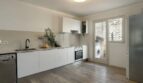 Helle Küche mit weißen Fronten, Einbaugeräten und Holzboden in moderner Wohnung in Palma de Mallorca