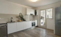 Helle Küche mit weißen Fronten, Einbaugeräten und Holzboden in moderner Wohnung in Palma de Mallorca
