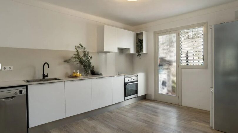 Helle Küche mit weißen Fronten, Einbaugeräten und Holzboden in moderner Wohnung in Palma de Mallorca