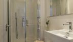 Modernes Badezimmer mit Glasdusche, weißem Waschbecken und Spiegelschrank in Palma-Wohnung