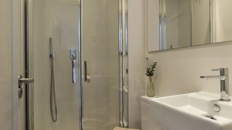 Modernes Badezimmer mit Glasdusche, weißem Waschbecken und Spiegelschrank in Palma-Wohnung
