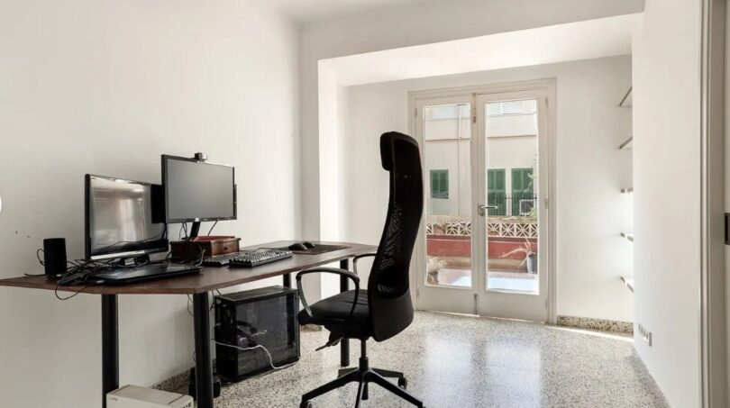 Helles Arbeitszimmer mit Schreibtisch, zwei Monitoren und Glastür zum Balkon in moderner Palma-Wohnung.