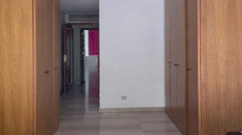 Schlafzimmer mit lila Bett, zwei Holzkleiderschränken und Blick in den Flur der Erdgeschosswohnung in Palma