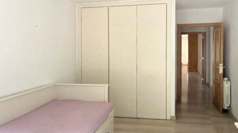 Helles Schlafzimmer mit Einzelbett, großem Einbauschrank und Zugang zum Flur in Erdgeschosswohnung Palma