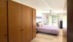 Helles Schlafzimmer mit Holzeinbauschränken, lavendelfarbenem Bett und Terrassenzugang in Erdgeschosswohnung Palma