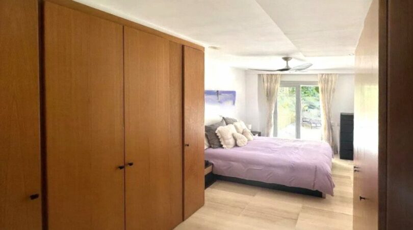 Helles Schlafzimmer mit Holzeinbauschränken, lavendelfarbenem Bett und Terrassenzugang in Erdgeschosswohnung Palma