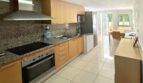 Moderne Einbauküche mit Granitarbeitsplatte, Holzfronten und Blick zur Terrasse in Erdgeschosswohnung Palma