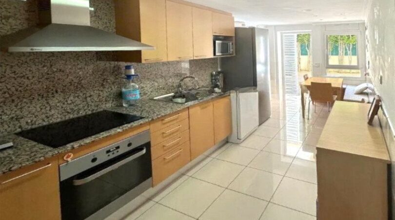 Moderne Einbauküche mit Granitarbeitsplatte, Holzfronten und Blick zur Terrasse in Erdgeschosswohnung Palma