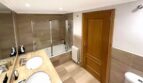 Helles Badezimmer mit Doppelwaschbecken, Badewanne mit Dusche, Holztür und Heizkörper in Erdgeschosswohnung Palma