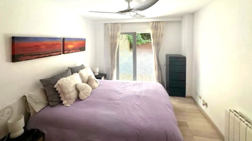 Helles Schlafzimmer mit Doppelbett, Deckenventilator und Terrassenzugang zum Garten der Erdgeschosswohnung in Palma.
