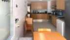 Helle Küche mit Essbereich, Holzmöbeln, modernen Einbaugeräten und Granitarbeitsplatten in Erdgeschosswohnung Palma