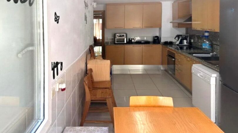 Helle Küche mit Essbereich, Holzmöbeln, modernen Einbaugeräten und Granitarbeitsplatten in Erdgeschosswohnung Palma