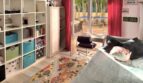 Kinderzimmer mit Regalwand, Schreibtisch, Spielteppich und Zugang zur sonnigen Terrasse mit Bäumen