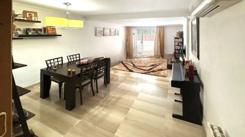 Helles Wohn-Esszimmer mit Fliesenboden, dunklem Esstisch und Terrassen-Ausblick in Erdgeschosswohnung Palma
