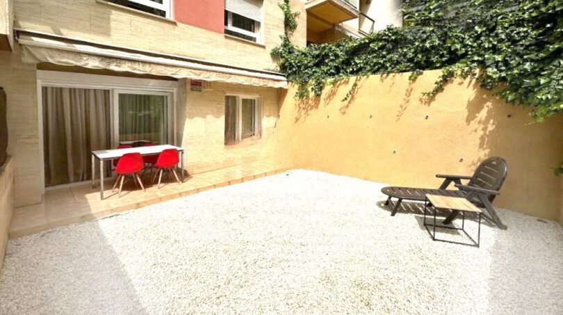 Sonniger Innenhof mit Kiesbelag, Lounge-Bereich und Esstisch, umgeben von begrünten Mauern