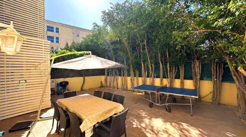 Sonnige Terrasse mit Essbereich, Sonnenschirm und Tischtennisplatte, umgeben von Bäumen in Palma de Mallorca