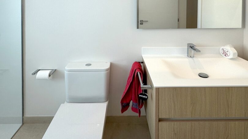 Modernes Badezimmer mit WC, Holzwaschtischunterschrank, Spiegel und Glasdusche in Erstbezug-Wohnung Palma