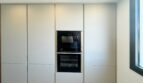 Moderne Einbauküche mit weißen Fronten, integriertem Backofen und Mikrowelle in exklusiver Erstbezug-Wohnung Palma