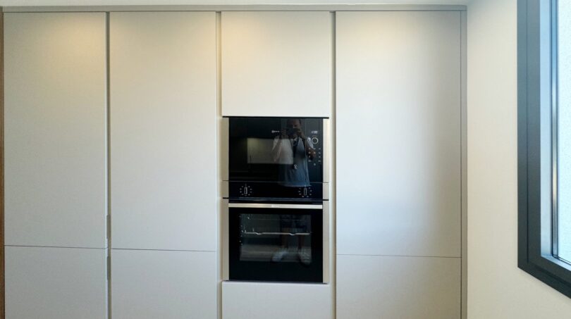 Moderne Einbauküche mit weißen Fronten, integriertem Backofen und Mikrowelle in exklusiver Erstbezug-Wohnung Palma
