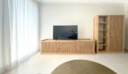 Helles Wohnzimmer mit Eichenholz-TV-Möbel, Regalschrank und bodenlangen Vorhängen in Erstbezugswohnung Palma