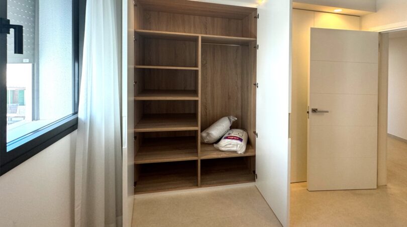 Offener Einbauschrank mit Holzregalen im hellen Schlafzimmer der Neubauwohnung am Parc de ses Estacions