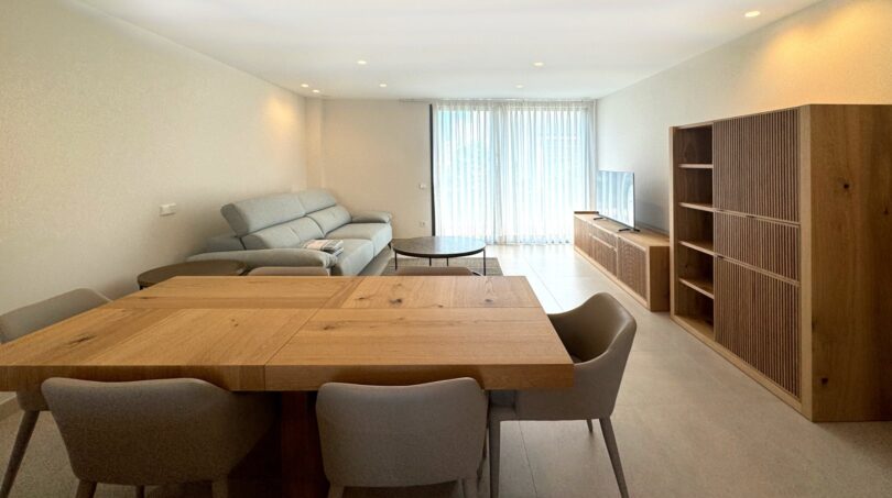 Modernes Wohn-Esszimmer mit Holztisch, grauer Couch und Einbauregal in exklusiver Erstbezug-Wohnung in Palma