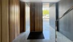 Eleganter Eingangsbereich mit Holzverkleidung, Marmorböden und Glasgeländer einer Luxuswohnung am Parc de ses Estacions