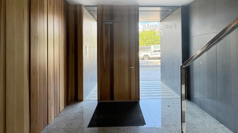 Eleganter Eingangsbereich mit Holzverkleidung, Marmorböden und Glasgeländer einer Luxuswohnung am Parc de ses Estacions