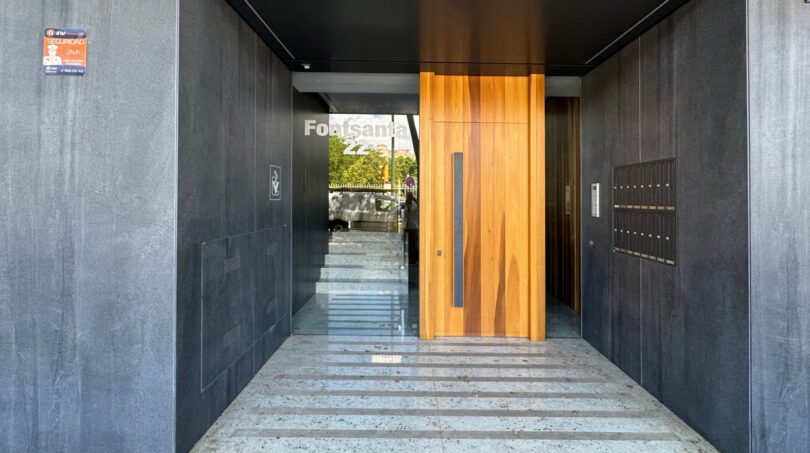 Moderner Eingangsbereich mit Holztür, Marmorstufen und Briefkastenanlage einer Luxuswohnung in Palma de Mallorca