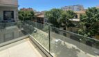 Moderner Glasbalkon mit Blick auf baumgesäumte Straße und Altstadt-Architektur in Palma de Mallorca