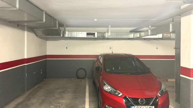 Tiefgarage mit nummerierten Stellplätzen und rotem Nissan Micra, Lüftungskanäle an der Decke, Palma de Mallorca