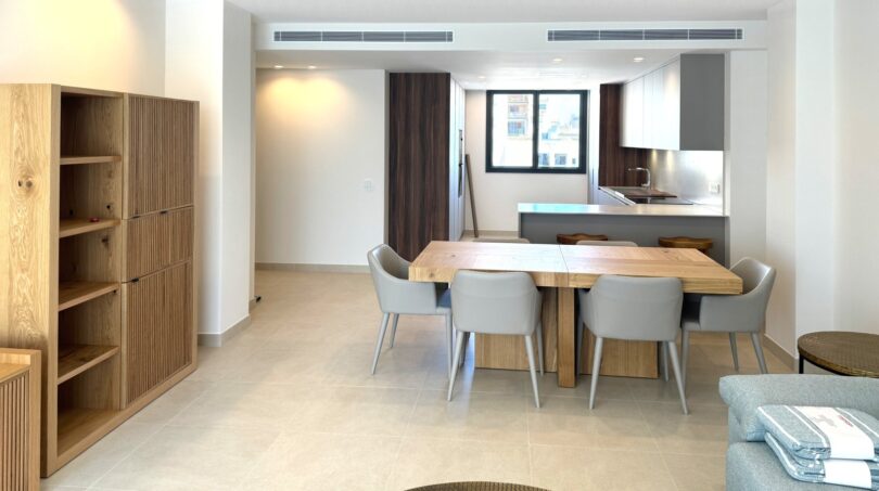 Heller Wohn-Essbereich mit Holztisch, moderner Küche und elegantem Einbauregal in exklusiver Erstbezugswohnung Palma