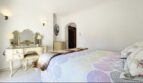 Elegantes Schlafzimmer der Strandvilla in Cala Vinyes mit antikem Schminktisch, Doppelbett und Bogentür.