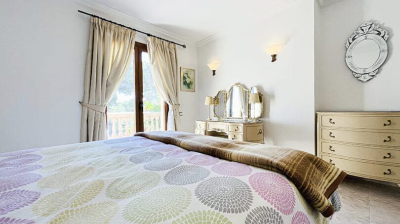 Helles Schlafzimmer der Villa in Cala Vinyes mit Doppelbett, Schminktisch und Balkonzugang.