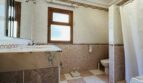Badezimmer der Villa in Cala Vinyes mit Marmorwaschbecken, Dusche, WC und Holzfenster.