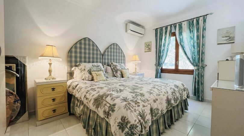 Helles Schlafzimmer der Villa in Cala Vinyes mit Doppelbett, Toile-de-Jouy-Bettwäsche und türkisen Akzenten.