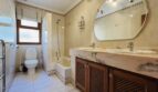 Elegantes Badezimmer mit Marmor-Doppelwaschbecken, Holzunterschrank, Badewanne und Dusche in Villa Cala Vinyes