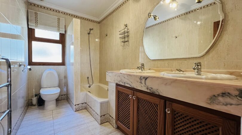 Elegantes Badezimmer mit Marmor-Doppelwaschbecken, Holzunterschrank, Badewanne und Dusche in Villa Cala Vinyes