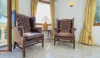 Elegantes Lesezimmer der Villa in Cala Vinyes mit zwei Chesterfield-Ledersesseln und goldenen Vorhängen.