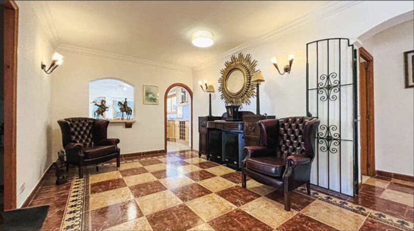 Eleganter Eingangsbereich der Villa in Cala Vinyes mit Schachbrettmarmorboden und Chesterfield-Sesseln.