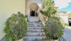 Steintreppe mit Rundbogen-Eingang, flankiert von Büschen – Außenbereich der exklusiven Villa in Cala Vinyes.
