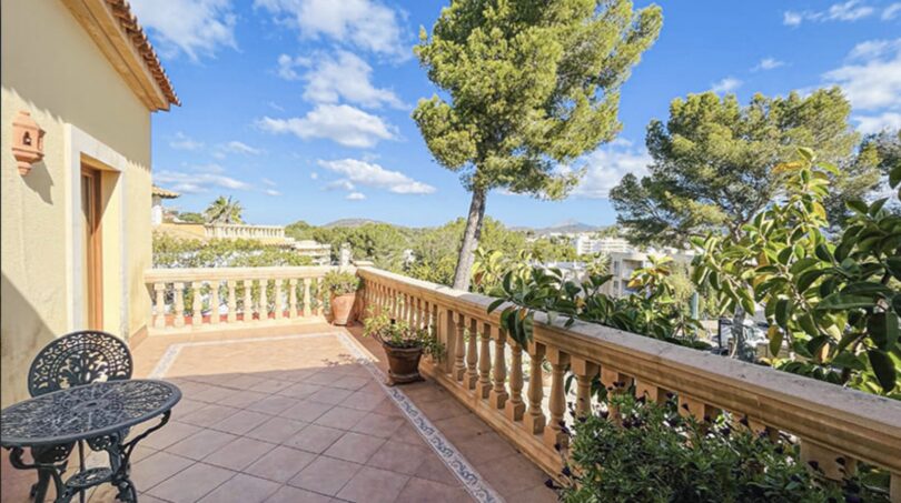 Sonnige Terrasse mit Balustrade, Gartenmöbeln und Blick auf Bäume und Berge in Villa Cala Vinyes
