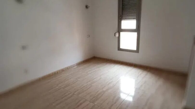 Leeres Schlafzimmer mit Holzfliesenboden, weißen Wänden und Fenster mit Rolllade in Maisonette-Wohnung El Molinar