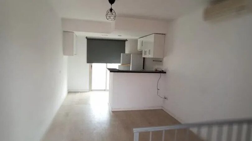 Offener Wohn-Kochbereich der Maisonette mit Holzboden, Einbauküche und Treppenaufgang in El Molinar