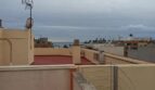 Dachterrasse der Maisonette in El Molinar mit Meerblick, Geländer und umliegenden Stadtdächern unter bewölktem Himmel.