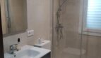 Modernes Badezimmer im Chalet Es Garrovers mit Glasdusche, WC und elegantem Waschtisch in Beige-Tönen.