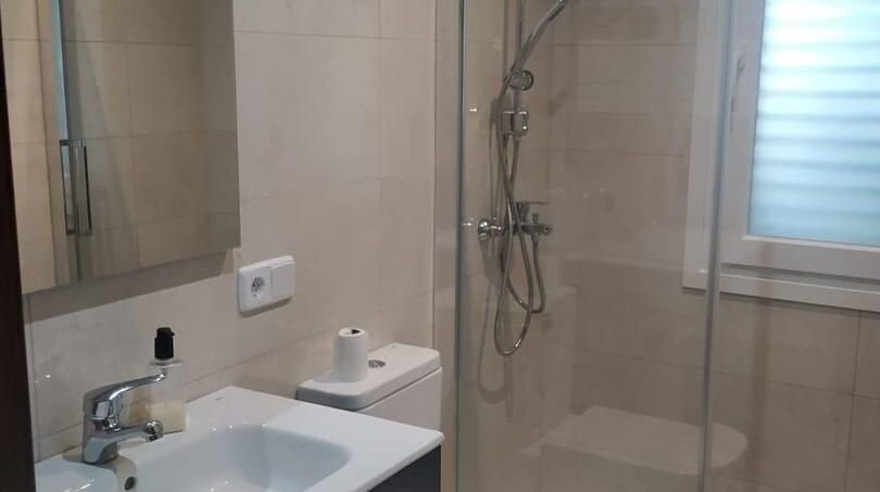 Modernes Badezimmer im Chalet Es Garrovers mit Glasdusche, WC und elegantem Waschtisch in Beige-Tönen.