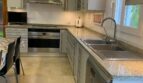 Moderne Küche im Chalet Es Garrovers mit Granitarbeitsplatte, Einbaugeräten und Marmorboden.
